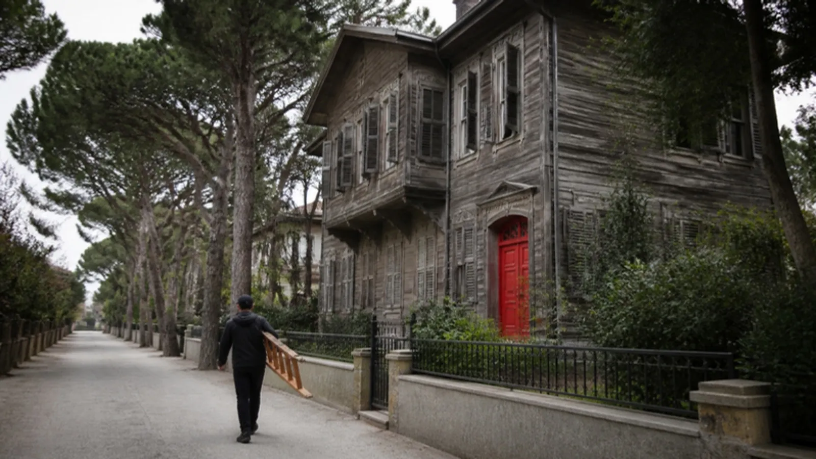 Adada bahçeli ahşap köşk ve merdiven taşıyan bakım görevlisi