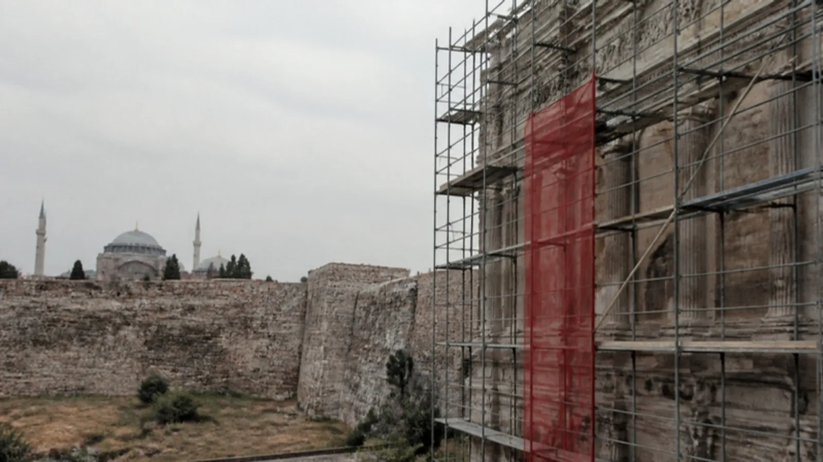 Tarihi yapı cephesinde restorasyon iskelesi, arkada surlar ve kubbeler