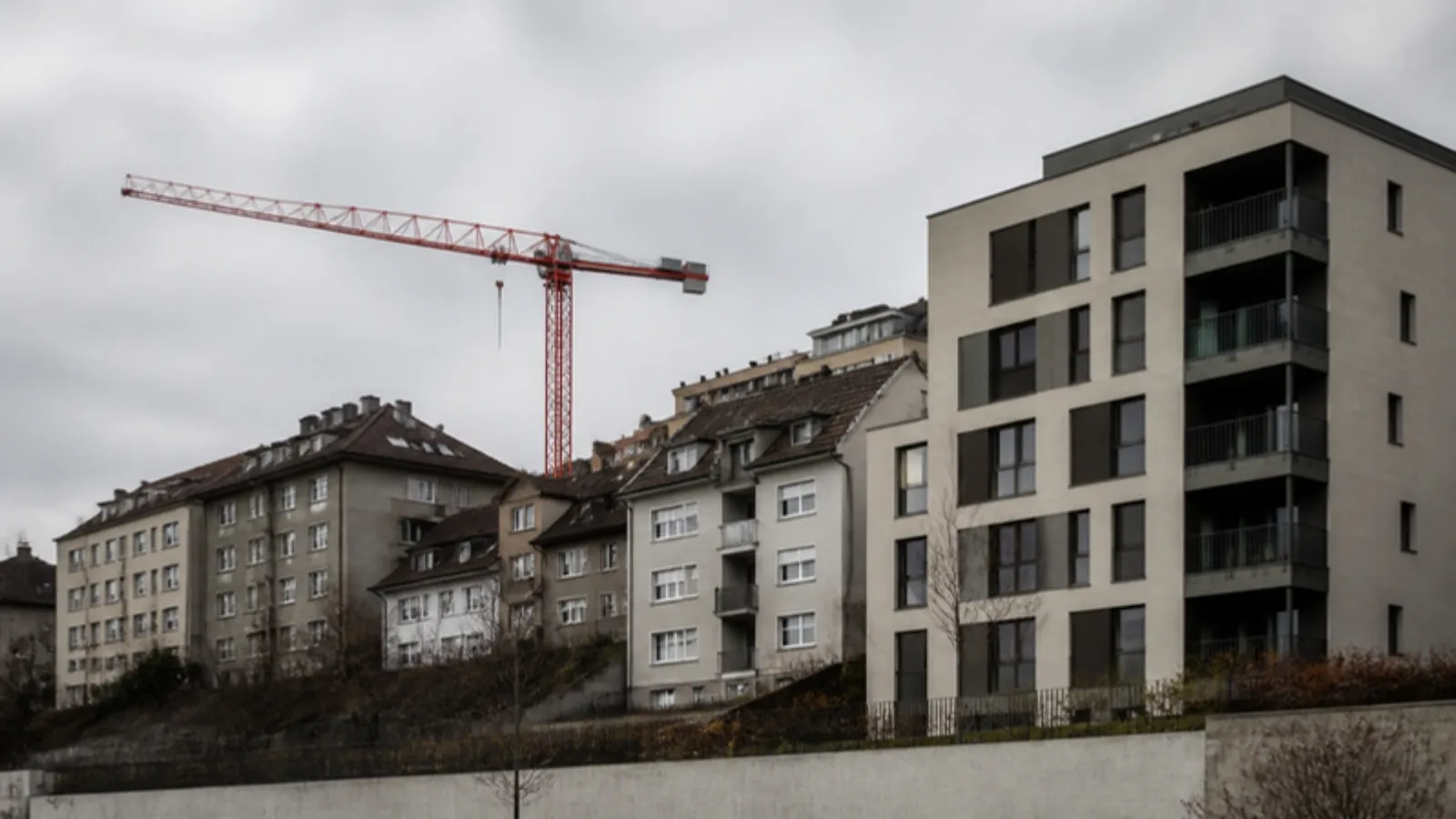 Yamaçta eski dört katlı apartmanlar ve yanında yükselen yeni konut bloğu