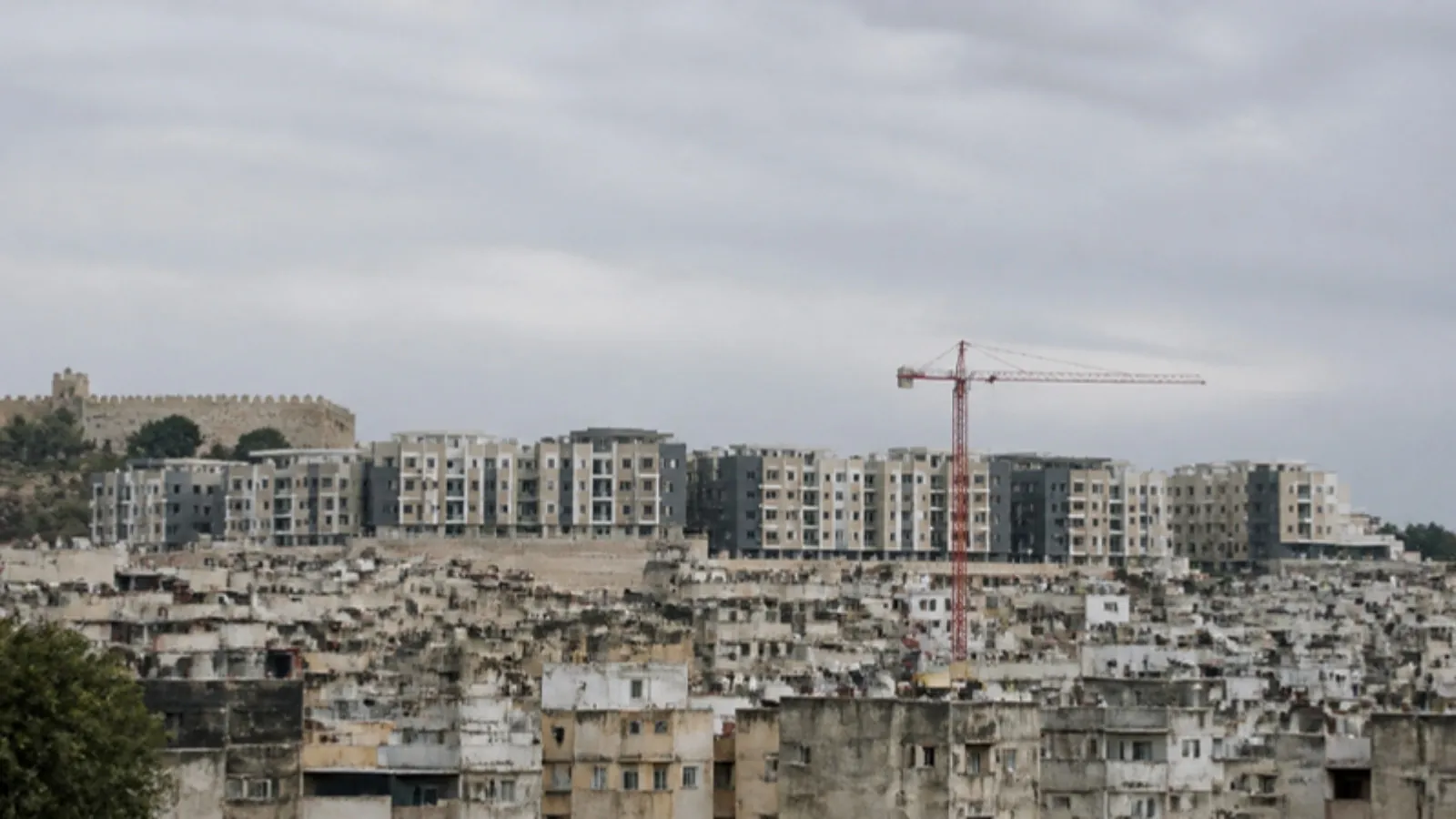 Önde eski yoğun apartmanlar, arkada tamamlanmış dönüşüm projesi